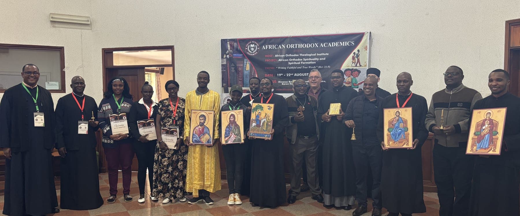Participants in the writers' workshop standing in a line beneath the project banner, a number of them holding painted icons.