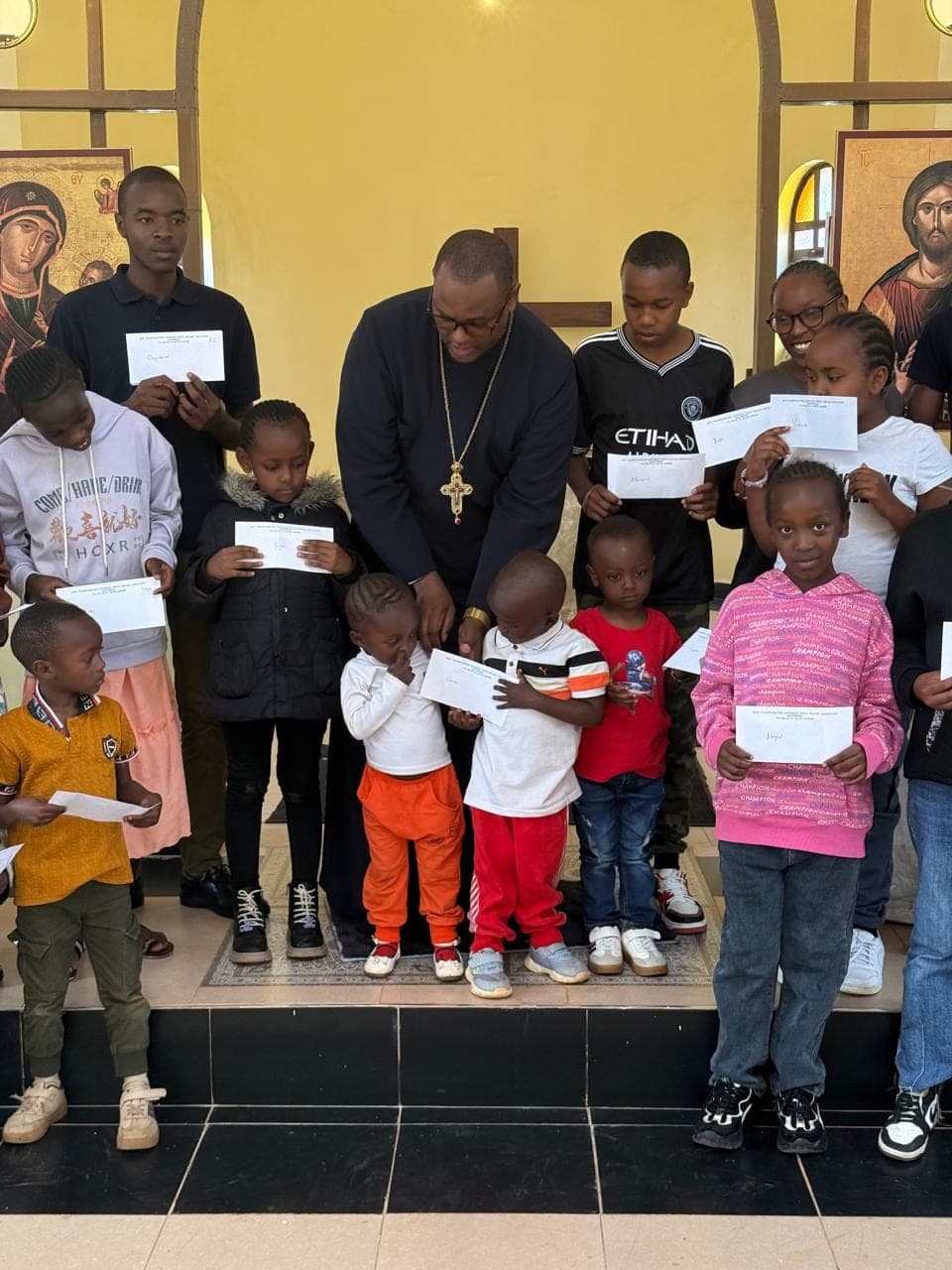 Younger recipients gathered around Fr Thiani, reading their award letters.