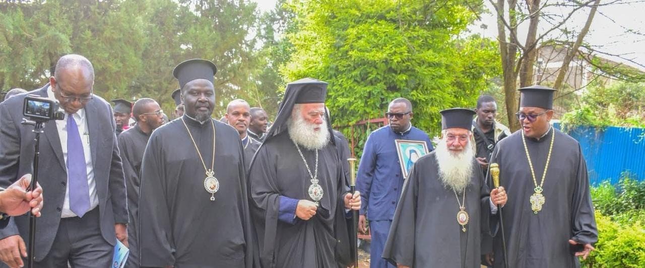 Fr Thiani, at right, walking in procession with Orthodox hierarchs and clergy along a church path.