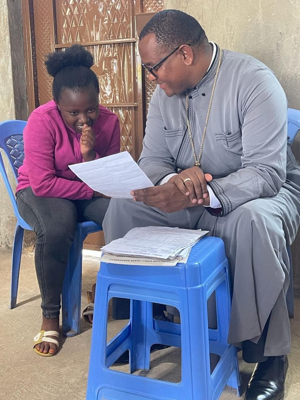 A pupil laughing as Fr Thiani goes through her results with her.
