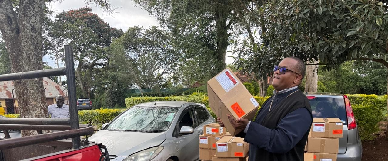 Fr Thiani unloading cartons of donated theological books beside a pickup truck.