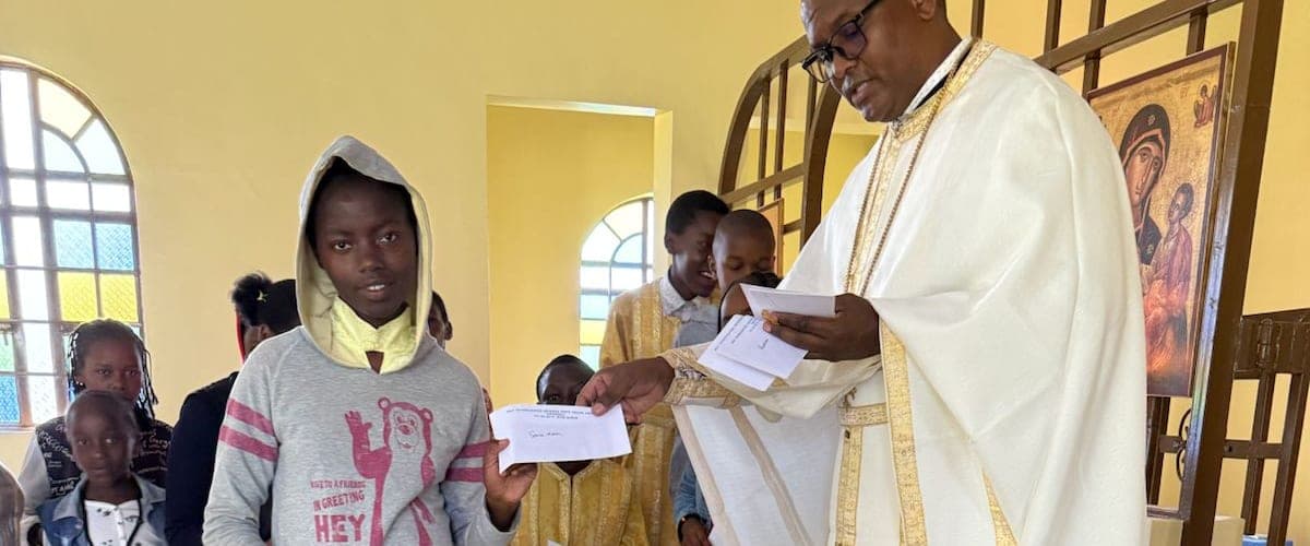 A pupil receiving her school-fee award letter from Fr Thiani during the liturgy.