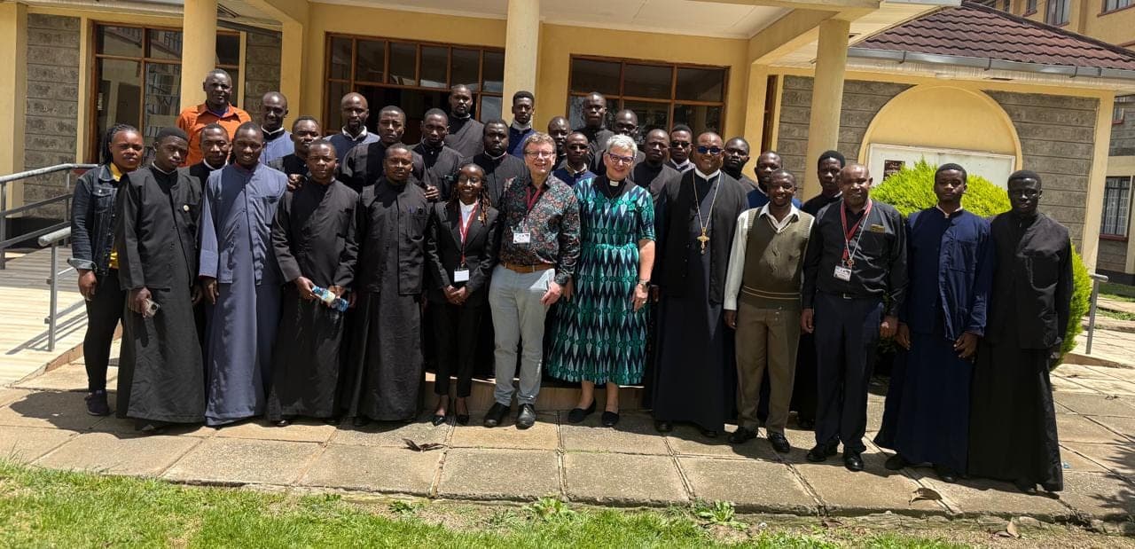 Visiting and local professors of theology photographed with Orthodox students outside a seminary building.